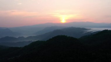 Kasepuhan Pasir Eurih, Banten, Endonezya 'daki yuvarlak tepelerin ardında gün doğumunun hava manzarası, doğal manzarayı aydınlatan yumuşak altın ışıkla.