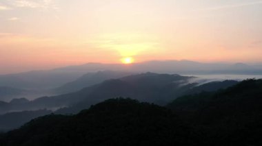 Kasepuhan Pasir Eurih, Banten, Endonezya 'daki yuvarlak tepelerin ardında gün doğumunun hava manzarası, doğal manzarayı aydınlatan yumuşak altın ışıkla.
