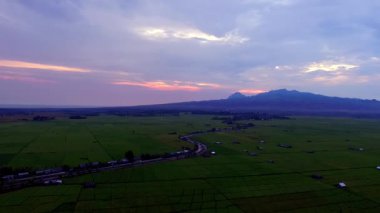 Geniş pirinç tarlalarının ve Lembor, Batı Manggarai, Doğu Nusa Tenggara 'daki uzak tepelerin havadan görünüşü, alacakaranlıktan önce altın gün batımında çekildi..