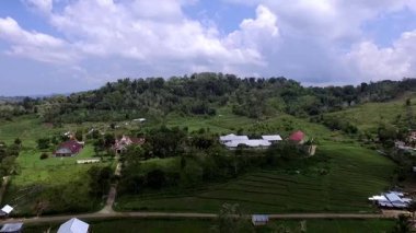 Flores, Endonezya 'daki uzak yamaç köylerinin havadan görünüşü, dağlık adalarda doğal topoğrafya, yemyeşil ve geleneksel kırsal yaşam sergileniyor..