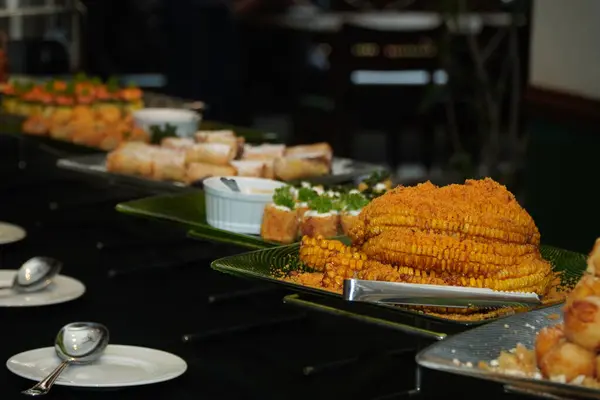İnce dilimlenmiş hindistan cevizi soslu ızgara mısır yanında Endonezya usulü çerezler, börek, kızarmış ikramlar ve iştah açıcı aperatifler servis edilir..