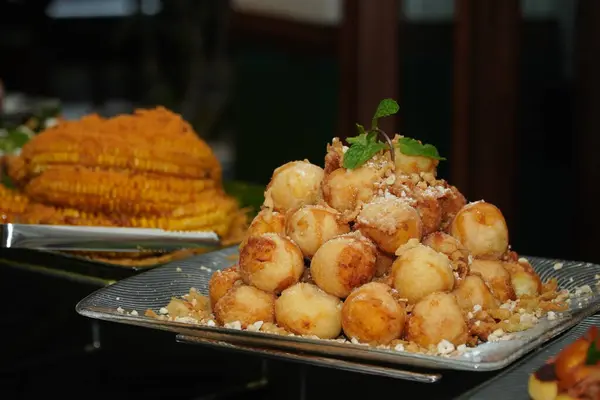 Büfe masasında ezilmiş fıstık ve nane yaprağıyla süslenmiş geleneksel Endonezya kızartma topları yığını. Özel etkinlikler veya yemek servisi için popüler yerel tatlı ikram.