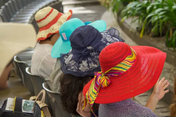 Bali, Endonezya 15 Ocak 2019 'da, renkli ve şık güneş şapkaları takan kadınların arka arkaya oturduğu canlı bir sahnenin fotoğrafı.. 