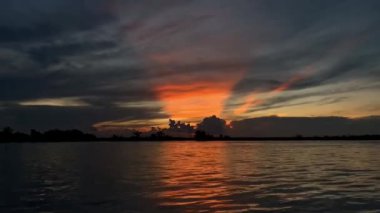 Güneş batarken Mahakam Nehri 'nin üzerinde altın saat. Suya sıcak renkler döküyor ve geleneksel tekne ve nehir kenarındaki evleri siluete boğuyor. Doğu Kalimantan' da barışı ve hayatın ritmini çağrıştırıyor..