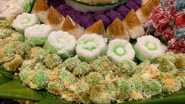 Muz yaprakları üzerinde renkli Endonezya geleneksel aperatifleri, katmanlı pirinç kekleri ve hindistan cevizi tatlılarının yer aldığı festival ve kültürel bir sunum.