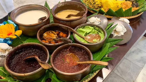 Geleneksel Endonezya tatlıları muz yapraklarının üzerindeki kil kaplarda sunuluyor. Siyah glüten pilavı, sago incileri, yeşil puding ve Hindistan cevizi sütü de dahil..