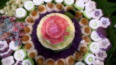 Muz yaprakları üzerinde renkli Endonezya geleneksel aperatifleri, katmanlı pirinç kekleri ve hindistan cevizi tatlılarının yer aldığı festival ve kültürel bir sunum.