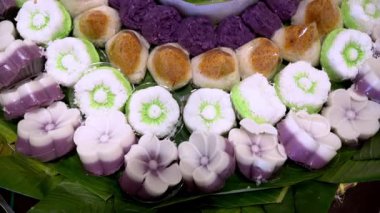 Muz yaprakları üzerinde renkli Endonezya geleneksel aperatifleri, katmanlı pirinç kekleri ve hindistan cevizi tatlılarının yer aldığı festival ve kültürel bir sunum.