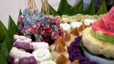 Muz yaprakları üzerinde renkli Endonezya geleneksel aperatifleri, katmanlı pirinç kekleri ve hindistan cevizi tatlılarının yer aldığı festival ve kültürel bir sunum.