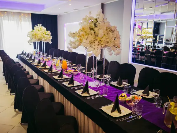Çiçek süslemeleri ve siyah dekorlu şık bir ziyafet masası.