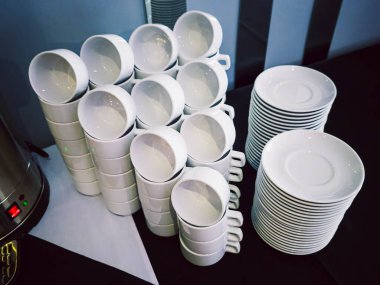 Doldurulmuş beyaz kahve fincanları ve çay tabakları yemek servisi için hazır.