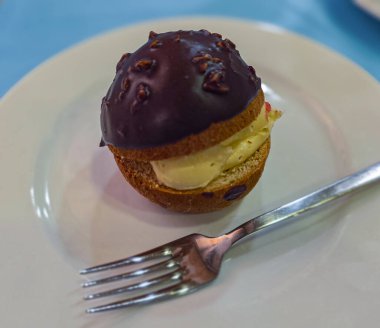 Beyaz bir tabakta servis edilen kremalı çikolata kaplı pasta.