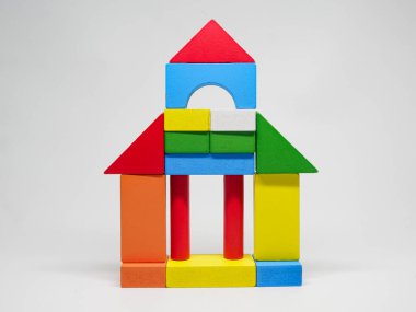 Çeşitli geometrik şekillerde tahta oyuncak blokları ve parlak renkler bir ev yapısı yaratmak için bir araya getirildi. Detayları ve materyali vurgulayarak yakın çekim.