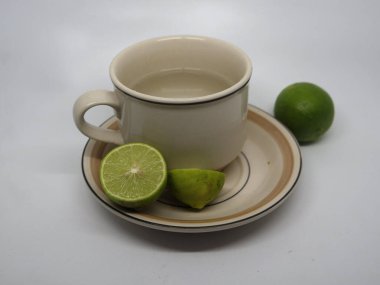 Beyaz arka planda bir bardak limon ve dilimlenmiş limon..