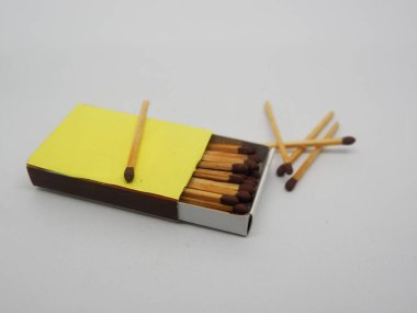 Beyaz arkaplanda sarı kutu ve kahverengi kibrit çöpleri