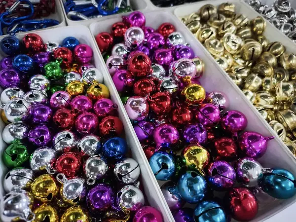 Renklere göre kutulara ayrılan sayısız parlak metal şıngırtılı çan manzarası. Koleksiyonda parlak altın, pırıl pırıl gümüş, zengin kırmızı, canlı pembe / mor, kraliyet mavisi, koyu mor ve zümrüt yeşili çanlar yer alıyor..