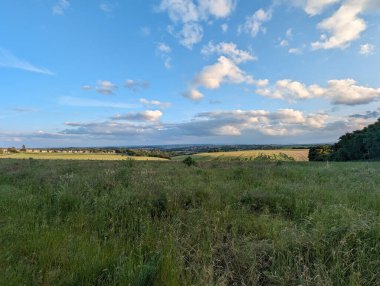 Pofuduk beyaz bulutlarla benekli parlak mavi bir gökyüzünün altında serinletici manzaralar sunan güzel, geniş bir manzara..