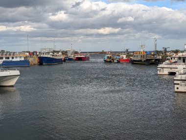 Bulutlu bir günde iskeleye yanaşmış çeşitli balıkçı tekneleriyle dolu bir liman. Bir sonraki maceraları için hazırlar..