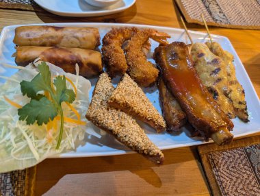 Yumurtalı börek, pirzola, susamlı tost ve tavuk şişleri de dahil olmak üzere çeşitli mezeler sunuluyor..