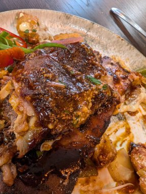 Pişmiş et, lezzetli soslar ve taze sebzelerin zarif bir şekilde servis edildiği gurme yemeğinin yakın çekim görüntüsü..