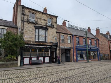 Bulutlu bir günde geleneksel bir bar, dükkan ve kaldırım taşı sokağının yer aldığı tarihi bir sokak manzarası nostaljik bir duyguyu çağrıştırıyor..