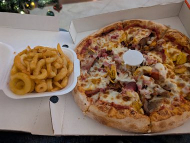 Bir kap patates kızartmasının yanında çeşitli malzemelerle lezzetli bir pizza, bu yemeğin tadını çıkarmaya hazır..