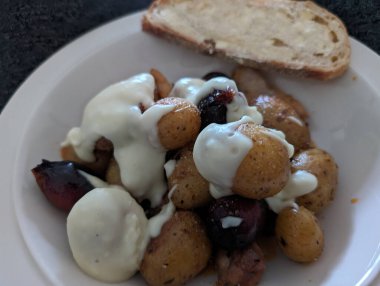 Bir tabak kızarmış patates ve soğan kremalı beyaz sosla kaplanır, ekmekle servis edilir..