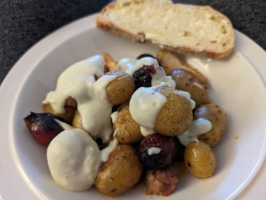 Bir tabak yağlı ekmekle servis edilen krema soslu kızarmış bebek patatesi. Lezzetli görünüyor..