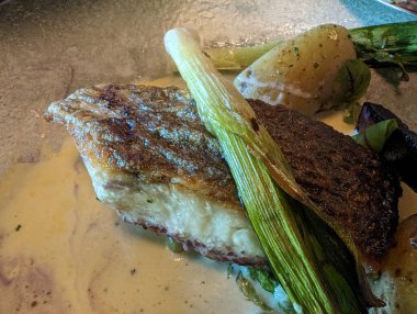 İçinde yeşil sebzeler ve kremalı sosla birlikte tavada kızartılmış balık bulunan lezzetli bir tabak. Mutfak kavramları için mükemmel..