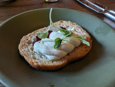 Lezzetli bir aperatif, krema, yeşillik ve bir parça kızarmış ekmek, yeşil bir tabakta sunulur..