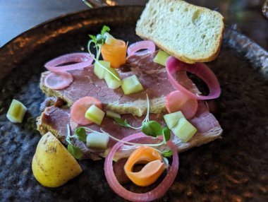 Renkli sebze turşusu ve bir dilim ekmek ile güzel düzenlenmiş bir tabak et. Yemek ustalıkla sunuldu..