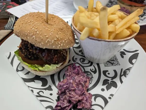 Patates kızartması ve lahana salatalı leziz bir burger tabakta servis edilir. Tatmin edici bir öğle yemeği için tam bir yemek..