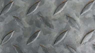 Endüstriyel metal plaka yüzeyine yakın çekim, yükseltilmiş desenli ve hafif pas, kaymayan zemin ve koruyucu yüzeylerde inşaat ve mühendislikte kullanılır.