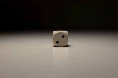Tahta zarların minimalist görüntüsü yumuşak nötr arka planda doğal tonlarda ve gölgelerde yumuşak dramatik ışıklandırma merkezli kompozisyonu olan iki numarayı gösteriyor.