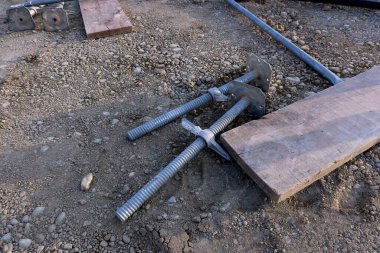İnşaat alanındaki çakıl zeminde duran ağır iskele vidaları. İskele desteği ve yükseklik seviyelendirme için ayarlanabilir temel plakalar. Endüstriyel ekipman