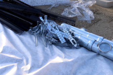 Metal parantezler, havalandırma parçaları ve inşaat alanındaki jeotextile kumaşa yerleştirilmiş çatı kenarı koruyucuları da dahil olmak üzere çeşitli çatı ve inşaat malzemeleri mevcuttur.