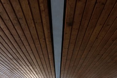 Merkezi metal kiriş mimari arka planı, doğrusal deseni ve kırsal dokusu olan ahşap bir tavanın simetrik perspektifi