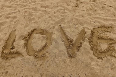Aşk kelimesi kumsalda yazıldı, üst görünüm doğal arka plan ayak izleri ve doku, romantizmin sembolü, basitlik, özgürlük ve tatil havası.