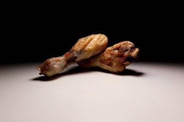 Asgari arkaplanda izole edilmiş iki tavuk budu dramatik ışıklandırma, yemek tasarımı, yemek pişirme veya mutfak reklamı için kızarmış kümes hayvanı eti konsepti.