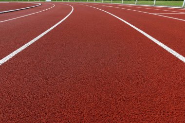 Beyaz şerit işaretli kıvrımlı kırmızı koşu yolu. Temiz kauçuk yüzeyi olan boş bir açık hava atletizm pisti. Spor, zindelik, rekabet, motivasyon ve kararlılık kavramı