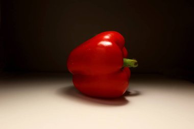Taze kırmızı dolma biber, dramatik stüdyo ışığı altında nötr bir zeminde izole edildi. Tatlı kırmızı biberli sebzelerin minimalist yemek fotoğrafları. Sağlıklı beslenme, organik üretim veya diyet konsepti