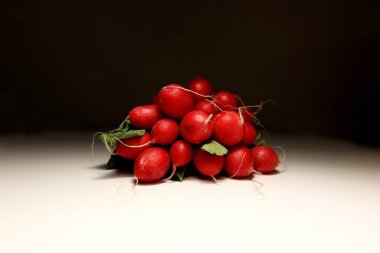 Yeşil yapraklı ve ince köklü taze kırmızı turp sürüsü, beyaz arka planda stüdyo çekimi. Sağlıklı beslenme, vejetaryen diyeti ya da mevsimlik yemek temaları için mükemmel.