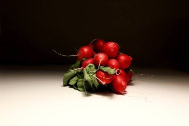 Sağlıklı yaşam tarzı, diyet, vejetaryen yiyecekler, temiz yemek veya tarım konsepti için yeşil yapraklı ve kökleri beyaz arka planda olan bir grup kırmızı turpun yan görüntüsü