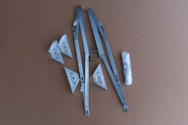 Metal mobilya menteşe mekanizmaları ve karton arka planda destek parantezleri. Yatak kaldırma mekanizması, mobilya montajı veya marangozluk donanımı bileşenleri