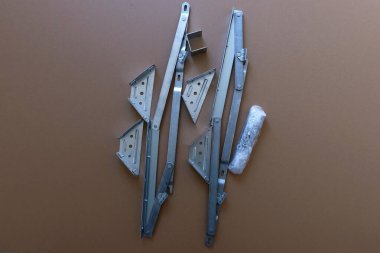 Yatağı kaldırma mekanizması için metal donanım seti, menteşeler, parantezler ve ambalaj pistonu dahil, karton arka planda düzenlenmiş. Tamir ya da montaj için endüstriyel mobilya parçaları