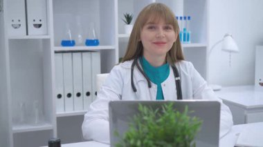 Kadın bir doktor bir masada oturur ve hastayı izler ve dinler. Boynunda steteskop olan beyaz bir önlük giymişti. Profesyonellik ve empati yapıyordu. Parlak, düzenli