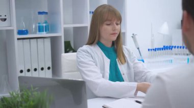 Otururken steteskopu tutan ve ayarlayan bir kadın doktorun yakın çekimi. Görüntü, sağlık ortamındaki tıbbi araçları ve profesyonelliği vurguluyor. Yüksek kalite 4k görüntü