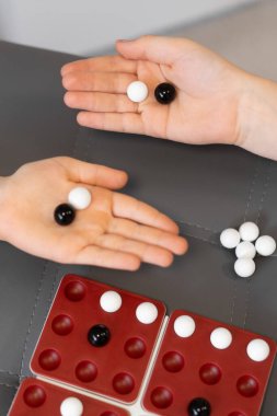 Çocuk elleri oyun tahtasına siyah ve beyaz misketler koyar. Oyuncular bir sonraki hamlelerine odaklanıyorlar, oyunu kazanmak için her parçayla strateji kuruyorlar. - Evet. Yüksek kalite fotoğraf