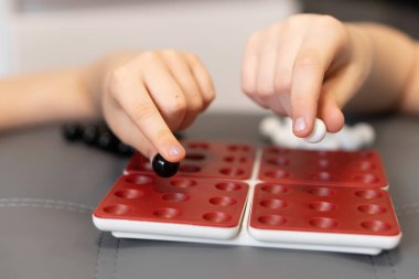 Çocuklar misketleri oyun tahtasına koyarlar, arkadaşlarıyla eğlenirler ve meydan okurlar. Oyun onların çocukluklarının neşeli bir parçasıdır. Çocuklar tahtada siyah beyaz bir oyun oynuyorlar.