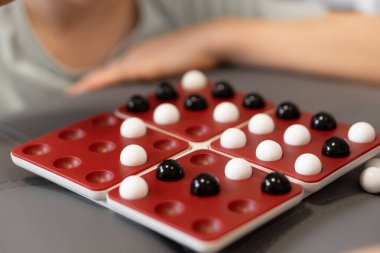 Çocuklar tahtaya siyah ve beyaz misketler koyup her hareketi dikkatlice planlıyorlar. Oyun onlara birlikte eğlenirken strateji öğrenme şansı sunuyor. Yüksek kalite fotoğraf